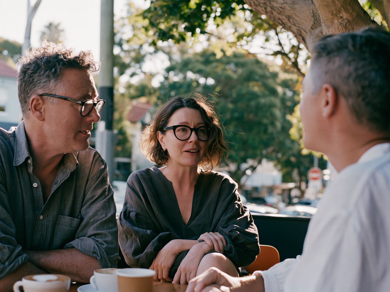 Three people talking over coffee